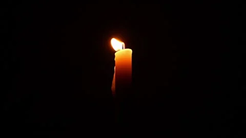 Lit yellow candle on dark background. Close up single candle flame isolated.. Stock Footage 344625410