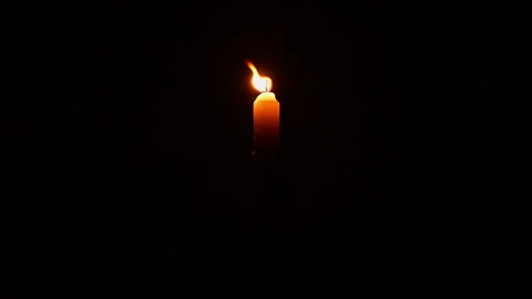Lit yellow candle on dark background. Close up single candle flame isolated.. Stock Footage 344625493