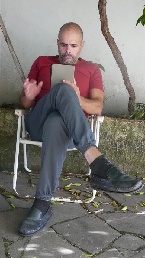 Literature: A man reads an e-reader in the backyard. A person reads an e-book Video stock 321033765
