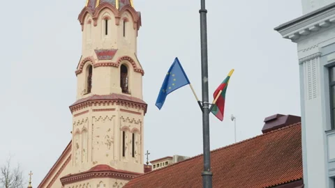 Lithuanian and EU flags waving on pole against church tower in Vilnius Stock-Footage 334719113