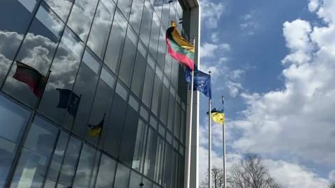 Lithuanian, EU and Ukrainian flags flying next to modern business center Stock Footage 239457419