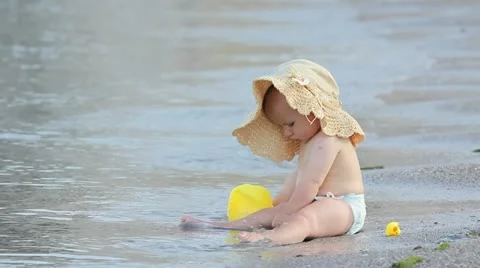 Litle baby with a big hat playing alone on the beach Stock Footage 12272151