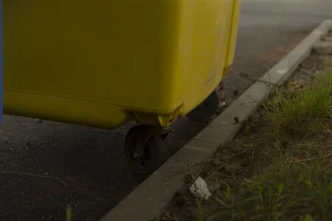 Littered gutter with damp asphalt and scattered trash nearby Stock Photos