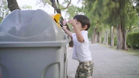 Little 2-3 year boy keep trash clean into park bin in nature public park Stock Footage 149917236