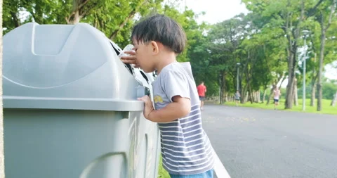 Little 2 year boy keep clean garbage to bin in city public park Stock Footage 138782811