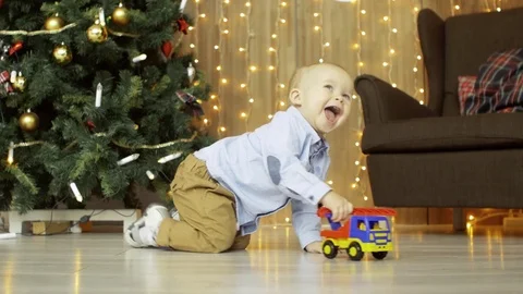 Little active blonde boy playing with a toy car on the floor, in the background Stock Footage 73718162