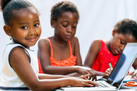 Little african girl doing homework on computer with friends. Stock Photos