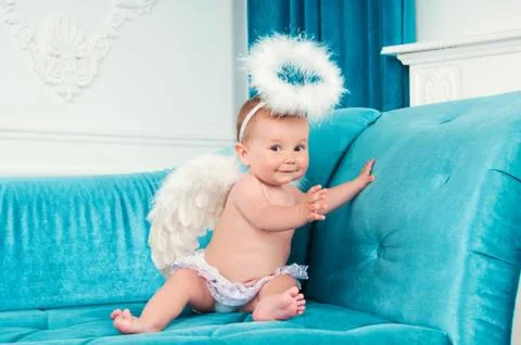 Little angel smiling and happy sitting on the couch. Stock Photos