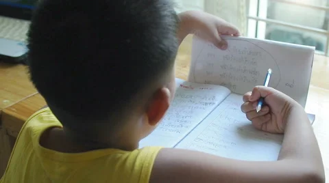 Little asian boy doing homework by use pencil writing on notebook. Stock Footage