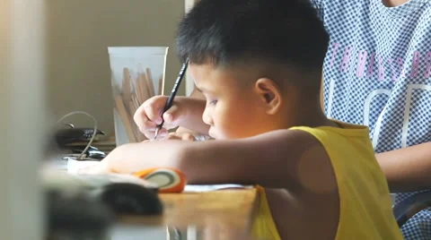 Little asian boy doing homework by use pencil writing on notebook. Stock Footage
