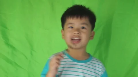 A little asian boy eats a cookie on green background 스톡 동영상 74607034