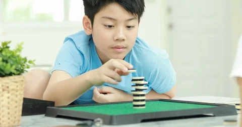 Little asian boy playing stack coin board game with young mother. Stock Footage 87976364