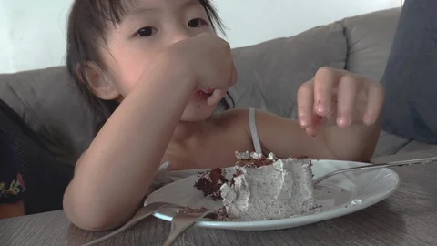 Little asian girl happily eats a cake. Stock Footage 120327770