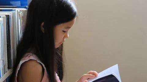 Little Asian girl reading a book in library Stock Footage