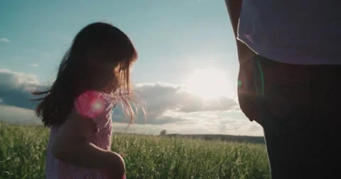 Little Asian girl running on the green field and holds the hand of his father Stock Footage