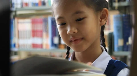 Little Asian student reading book in library Stock Footage