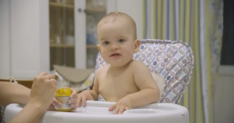 Little baby boy eats vegetable puree in the kitchen in the evening Stock Footage 113419348