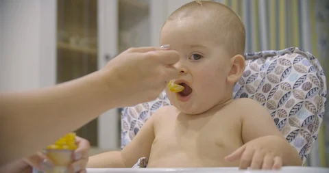 Little baby boy eats vegetable puree in the kitchen in the evening. Stock Footage 113419368