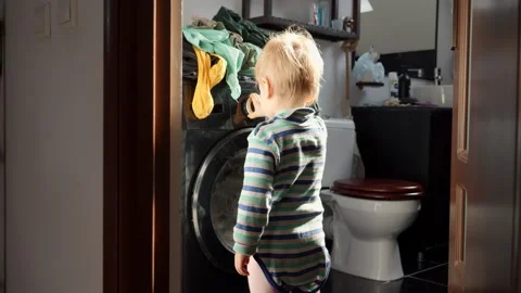 Little baby boy pressing knobs and buttons on working washing machine. Doing hou 스톡 동영상 238583260