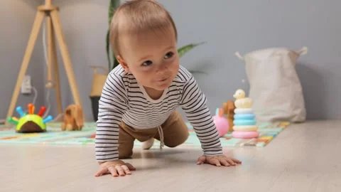 A little baby is exploring the floor by crawling towards various toys in a Vídeos de archivo 299938860
