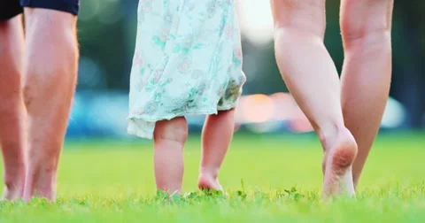 Little baby First Steps. Family feet walk on grass Close Up . SLOW MOTION 4K Stock Footage