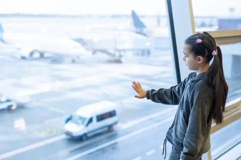 Little baby girl waiting boarding to her flight in airport transit hall and Stock Photos