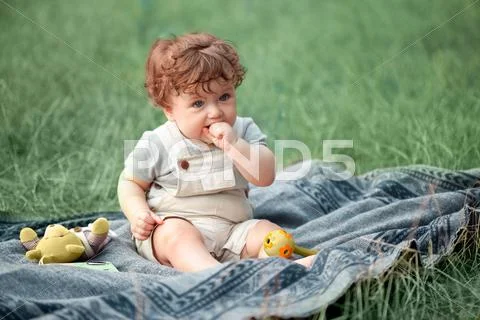 The little baby or year-old child on the grass in sunny summer day Stock Photos