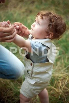 The little baby or year-old child on the grass in sunny summer day Stock Photos
