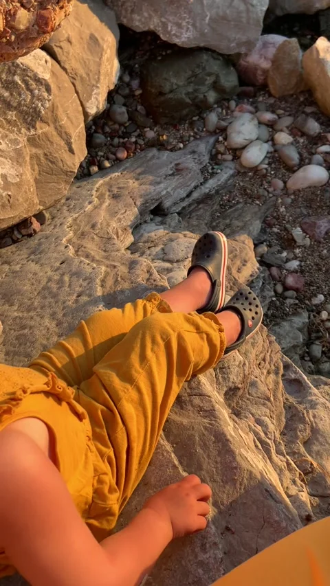 A little baby at sunset throws pebbles into the sea Stock Footage 236908690