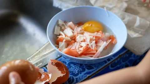 Little baby's hands learning to crack an egg to make crab stick omelette at home Stock Footage 103492534