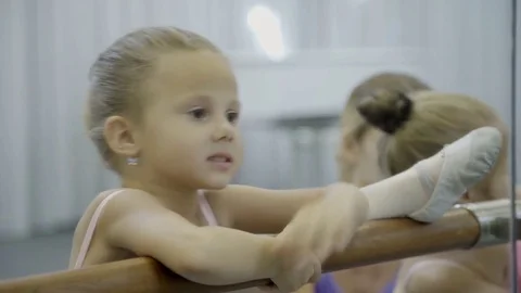 Little ballet dancer stretching her leg on the barre and learns how to lean Video stock 83155347