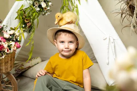 Little beautiful boy in Easter decor wearing a hat with a small duck, religious Foto stock