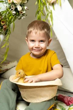 Little beautiful boy in Easter decor wearing a hat with a small duck, religious Stock Photos