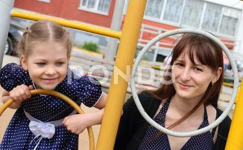 Little beautiful girl and her mother plays on children playground Stock Photos