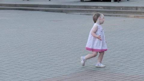 A little beautiful girl in a dress is dancing on the street in the park Stock Footage 156068992