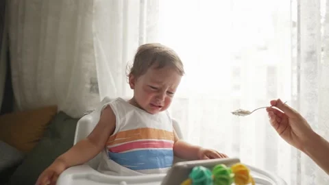 Little blond boy does not want to eat a meal that gives him a parent and cry Stock Footage 195122604
