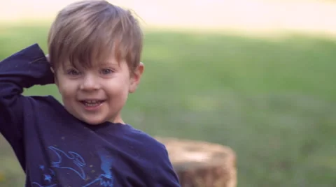 Little blond boy looking at camera waving and playing with toy in slow motion Video stock 48883010