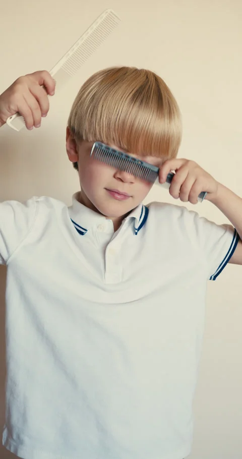 Little blond boy playfully combing his hair 스톡 동영상 346983264