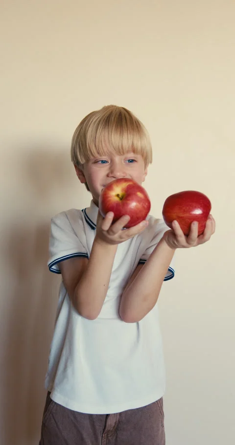 Little blond boy playing with two red apples Vidéo 346983408