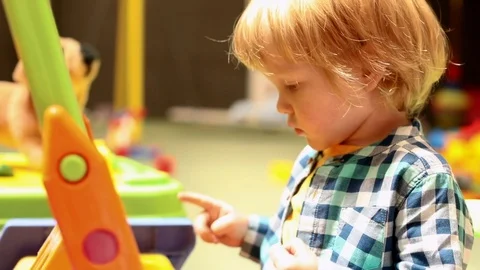 LIttle blonde boy learning to draw in playroom children entertainment center Stockbeeldmateriaal 113386559