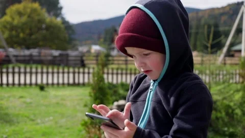 Little blonde boy using smartphone mobile looking photos tapping touchscreen 스톡 동영상 164663912