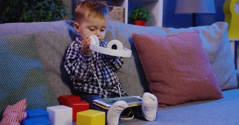 Little blonde nice boy taking on big white headphones and preaparing for Stock Footage 82920919
