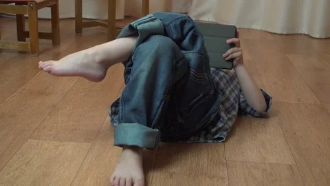 Little boy 4 years old brunette in a blue checkered shirt playing on a tablet Stock Footage 75845001