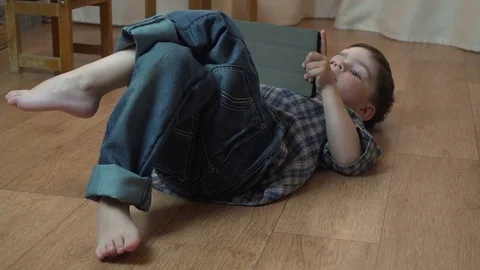 Little boy 4 years old brunette in a blue checkered shirt playing on a tablet Stock-Footage 75845600