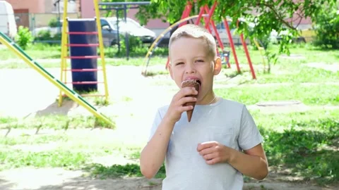 Little boy 7-8 years old with pleasure eating delicious ice cream. Slow motion Stock Footage 157243553