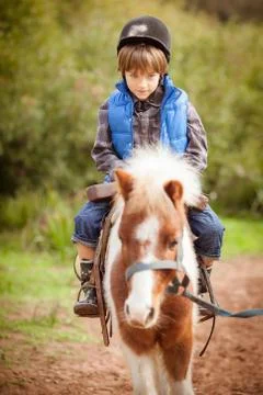 Little boy (8-9) riding pony horse Stock Photos
