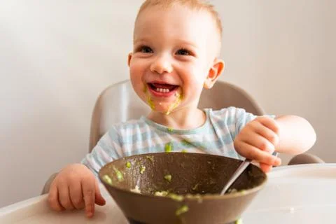 Little boy alone eats puree from a plate. Stock Photos