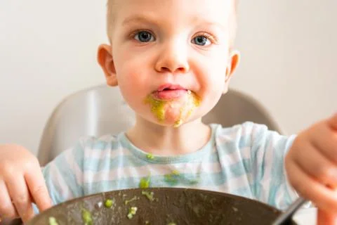 Little boy alone eats puree from a plate. Stock Photos