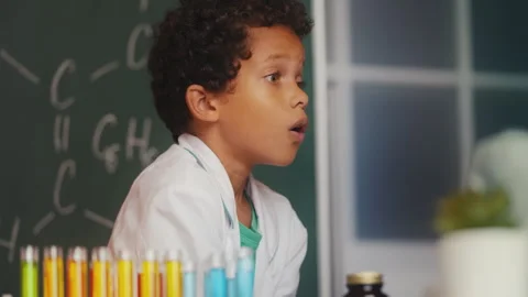 Little boy analyzing lab sample with a magnifying glass, shocked by test results Video stock 279880489
