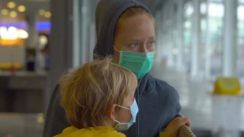 Little boy and his mother in a medical face masks in an airport waiting for Stock Footage